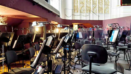 Orchestra pit of the Opera and Ballet Theatre. A break in the rehearsal of musicians in the orchestra pit. Music stands, chairs, music notes under the theater stage. Arrangement of an orchestra pit. photo
