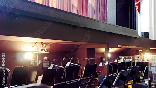 Arrangement of an orchestra pit in the opera and ballet theatre. Empty seats in the orchestra pit during a break in the rehearsal of the musicians. Music stands and notes under the theater stage. photo