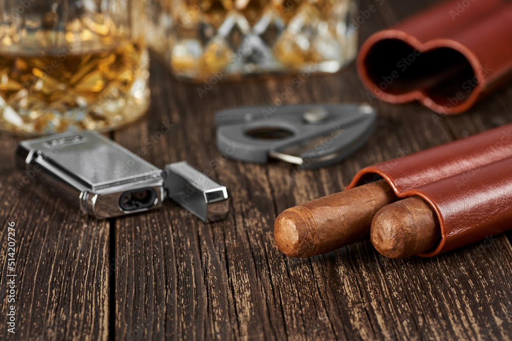 Two Cuban cigars, a cutter and a lighter in a leather case on an old brown table