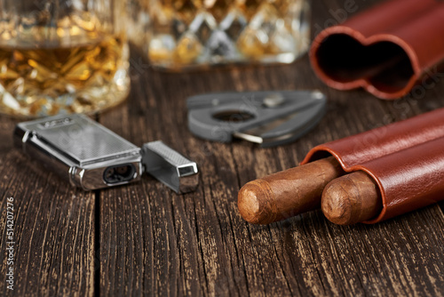 Two Cuban cigars, a cutter and a lighter in a leather case on an old brown table