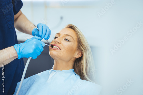 European young woman sitting in medical chair while dentist fixing her teeth at dental clinic. Image of satisfied young woman sitting in dental chair at medical center 