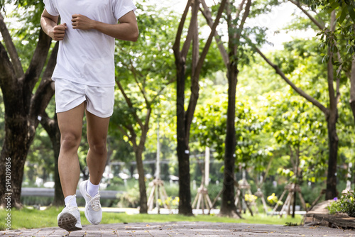 Asian handsome man in white shirt running in park. Concept for health lifestyle in park.