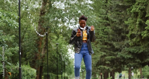 Wallpaper Mural Confident woman in headphones relaxes and dances flipping through music on her smartphone. Torontodigital.ca