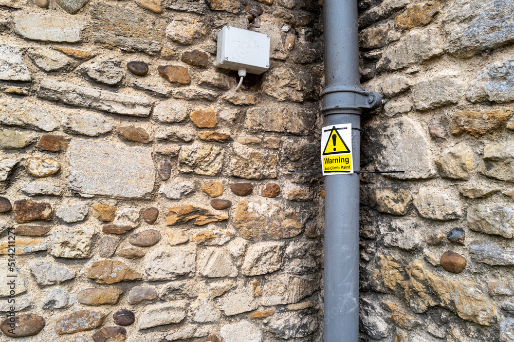 Anti Climb Paint warning sign seen attached to a newly painted wrought iron drainpipe seen on a church exterior. Used to help prevent lead roof theft in a rural English community. Anti Climb Paint warning sign seen attached to a newly painted wrought iron drainpipe seen on a church exterior. Used to help prevent lead roof theft in a rural English community.