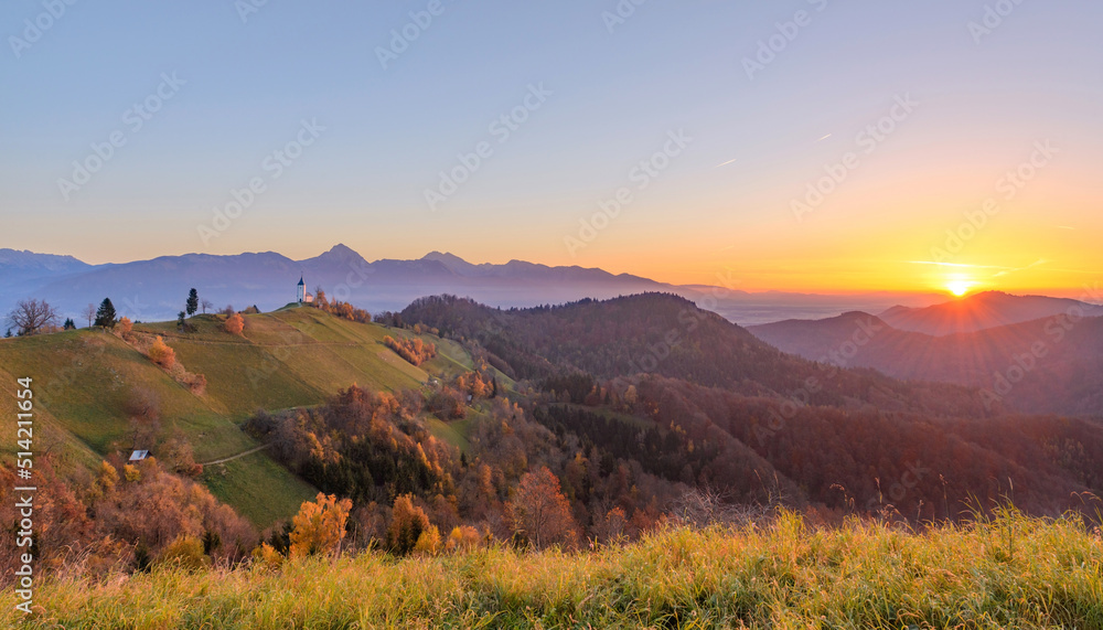 Church on the hill at sunrise. Beautiful scenery at Jamnik, Slovenia. Panoramic view of the mountains behind the church in the early morning.