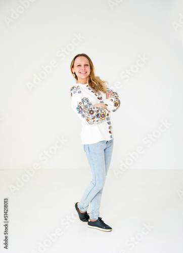 portrait of beautiful smiling young woman in ukrainian white embroidery posing in white studio
