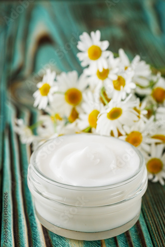 Chamomile cream in glass jar on the wooden background