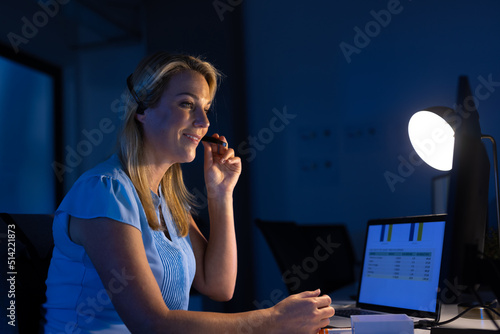 Female caucasian customer service executive talking over headset and using computer at desk