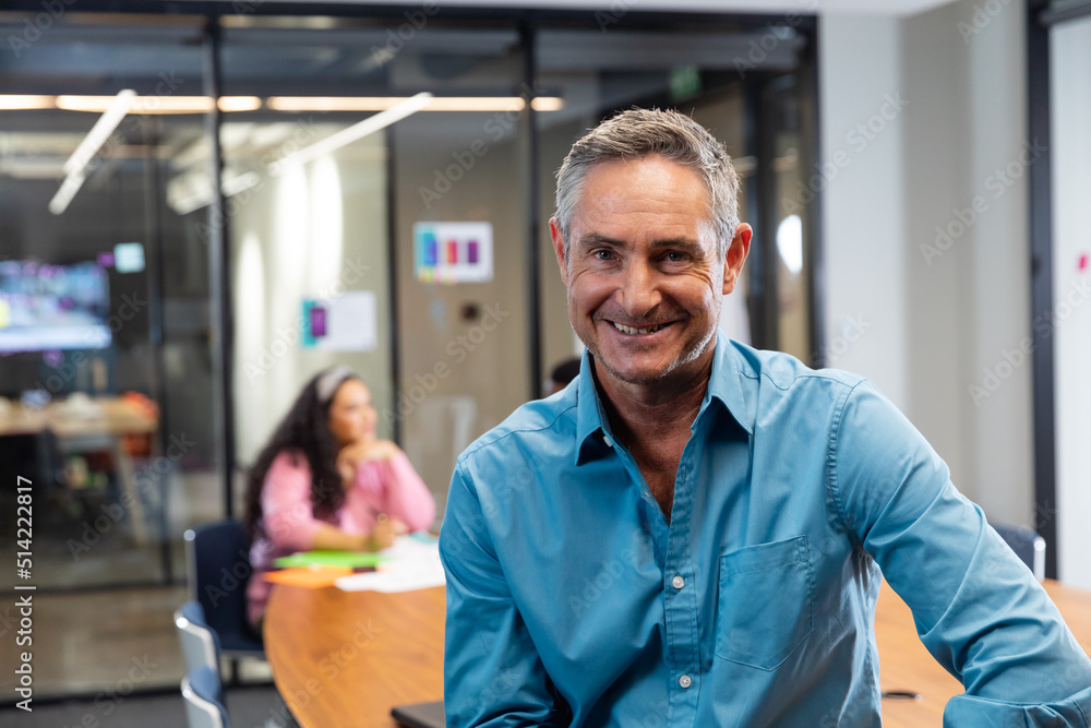 Portrait of smiling mature caucasian businessman in board room at office Portrait of smiling mature caucasian businessman in board room at office