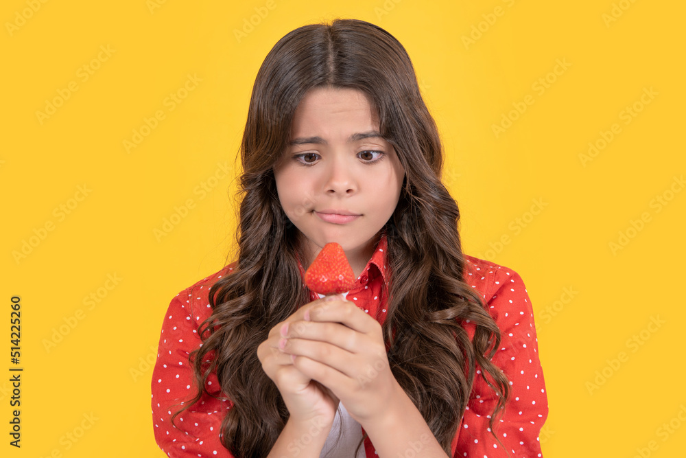 upset teen girl hold strawberry on yellow background upset teen girl hold strawberry on yellow background