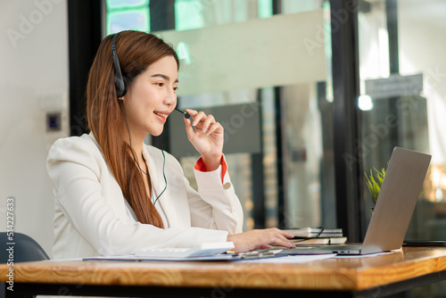 Wallpaper Mural Successful Asian businesswoman sitting at her desk wearing headphones talking to a customer meeting online with a laptop. financial accounting concept Torontodigital.ca