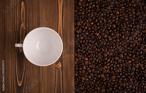 Roasted coffee beans and coffee cup on wooden texture. Top view brown coffee beans texture for backdrop and wallpaper use
