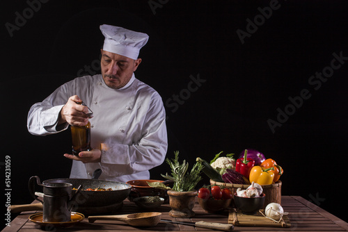 Male chef in white uniform ready to pouring vinegar onto the cooking pan
