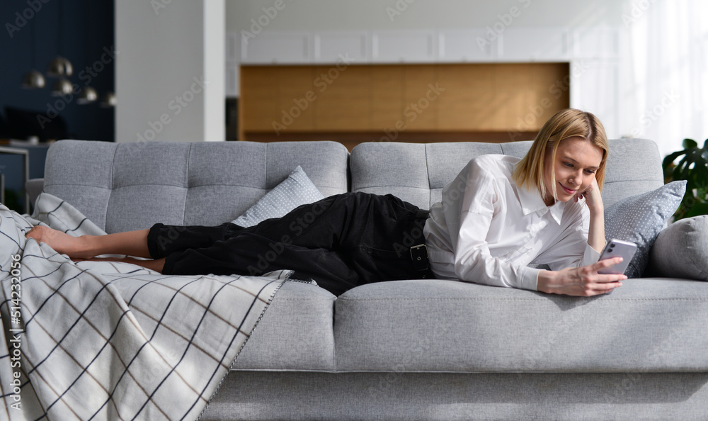 Obraz premium Woman with smartphone at home lying on sofa.