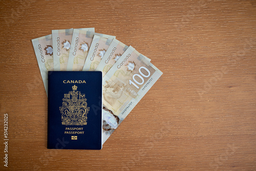 Calgary, Alberta - June 29, 2022: Canadian passport with Canadian 100 dollar bills. photo