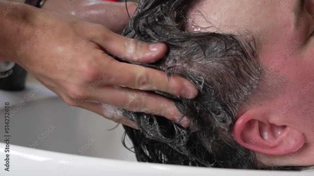 Slow motion static shot of a man getting his hair washed.