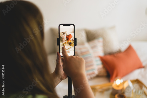 Video blog. A young woman is filming home goods for her online store on her phone camera. Running a video blog. A vlogger broadcasts online using a phone. Social networks,stay at home and quarantine.