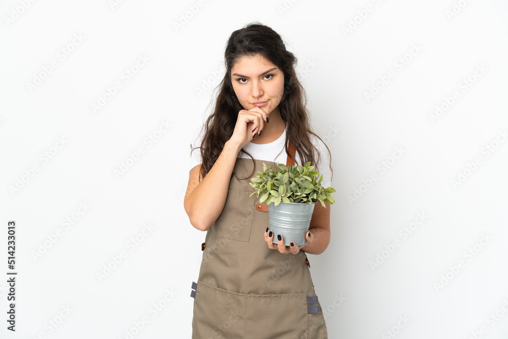 Young Russian gardener girl holding a plant isolated thinking Young Russian gardener girl holding a plant isolated thinking