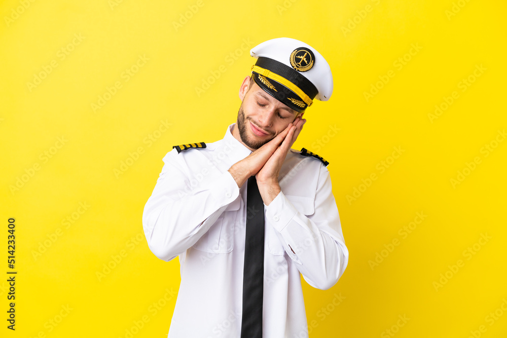 Airplane caucasian pilot isolated on yellow background making sleep gesture in dorable expression Airplane caucasian pilot isolated on yellow background making sleep gesture in dorable expression
