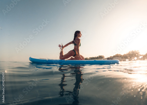 exercises on a paddle sup board in the ocean at sunrise