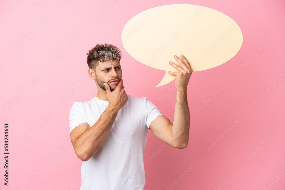 Young handsome caucasian man isolated on pink background holding an empty speech bubble and thinking Young handsome caucasian man isolated on pink background holding an empty speech bubble and thinking