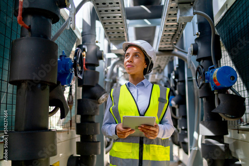 Portrait of engineer or technician worker woman stay in area of pipe network with day light and also look at the right side in constuction area. photo