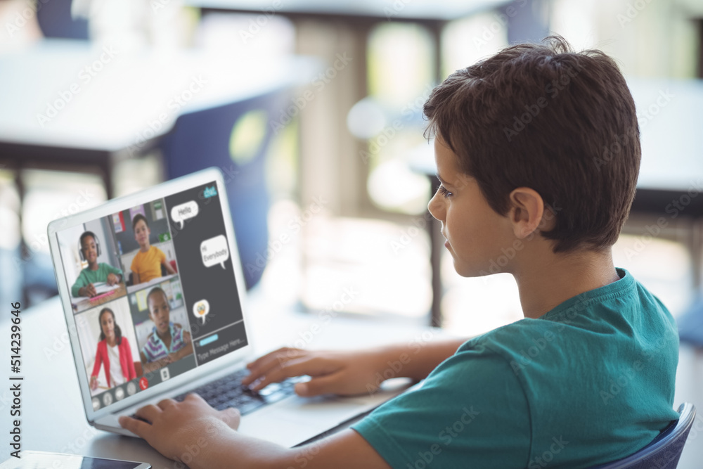 Side view of caucasian boy studying online through video call over laptop on table at home Side view of caucasian boy studying online through video call over laptop on table at home