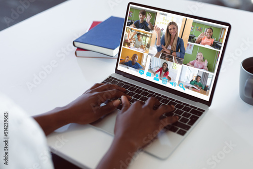 Cropped hands of african american student tying laptop keys during online lecture on table at home