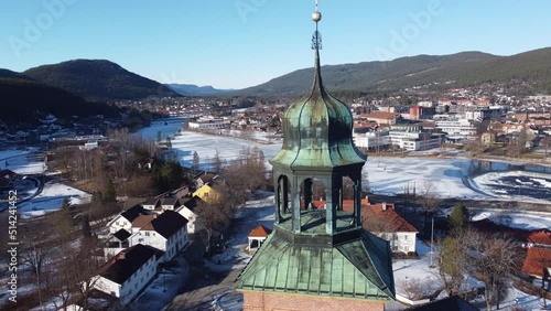 Beautiful winter aerial view of Kongsberg city with top of Church tower in foreground - Aerial slowly orbiting round church spire while revealing full panormaic city view at sunny winter day photo