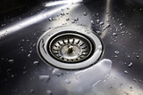 Drain in stainless steel sink with a mesh lid, and water drops close-up