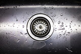 Drain in stainless steel sink with a mesh lid, and water drops close-up