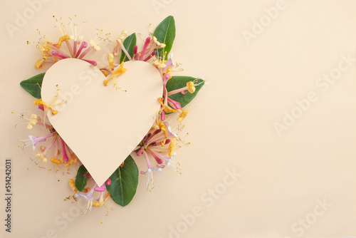 heart shape made of colored cardboard hiding caprifoi flowers. romantic  backdrop with beautiful flowers. photo