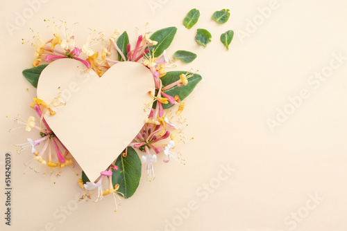 Heart made from lonicera periclymenum belgica flowers and beige paper cut.  photo