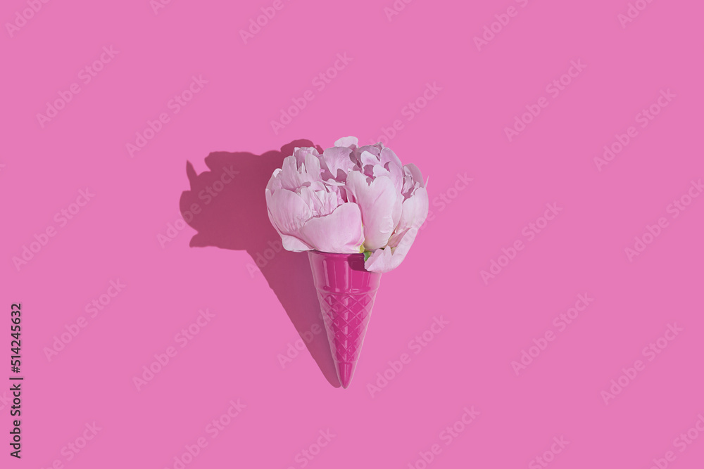 Creative pink toy ice cream cone with pink peony fluffy flower on pink minimal background with copy space flat lay. Botany idea for summer or spring wallpaper or greeting card. Creative pink toy ice cream cone with pink peony fluffy flower on pink minimal background with copy space flat lay. Botany idea for summer or spring wallpaper or greeting card.