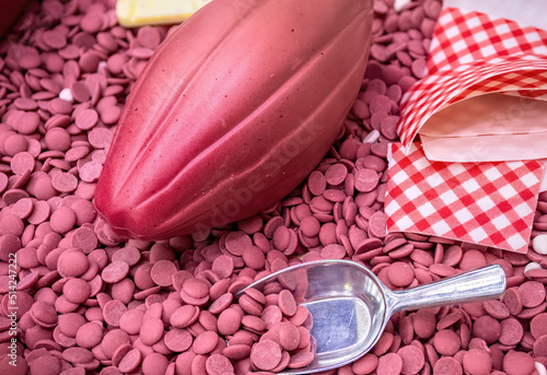 Fotografia Ruby chocolate cocoa fruit against the background of ruby chocolate drops top view