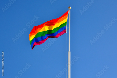 The gay pride flag against blue sky