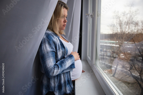 Young pregnant woman in home clothes looks out the window Free Download Young pregnant woman in home clothes looks out the window - GFXLoad