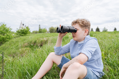 An 11-year-old boy on a walk, look through binoculars.