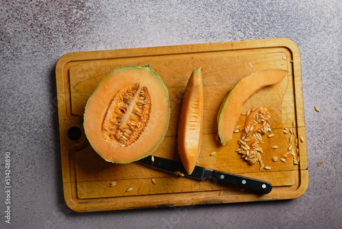 Top view of a cut cantaloupe melon, on a wooden cutting board.
