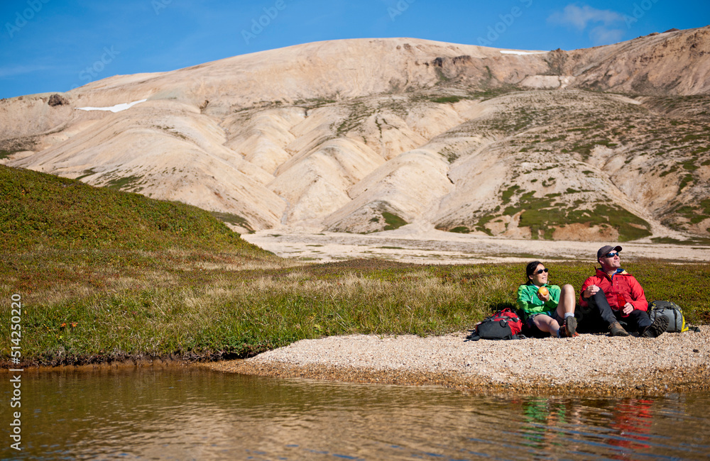 couple resting during a hike in the remote east fjords of Iceland couple resting during a hike in the remote east fjords of Iceland