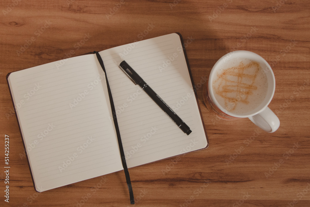 open notebook with a mug of coffee latte on the side open notebook with a mug of coffee latte on the side
