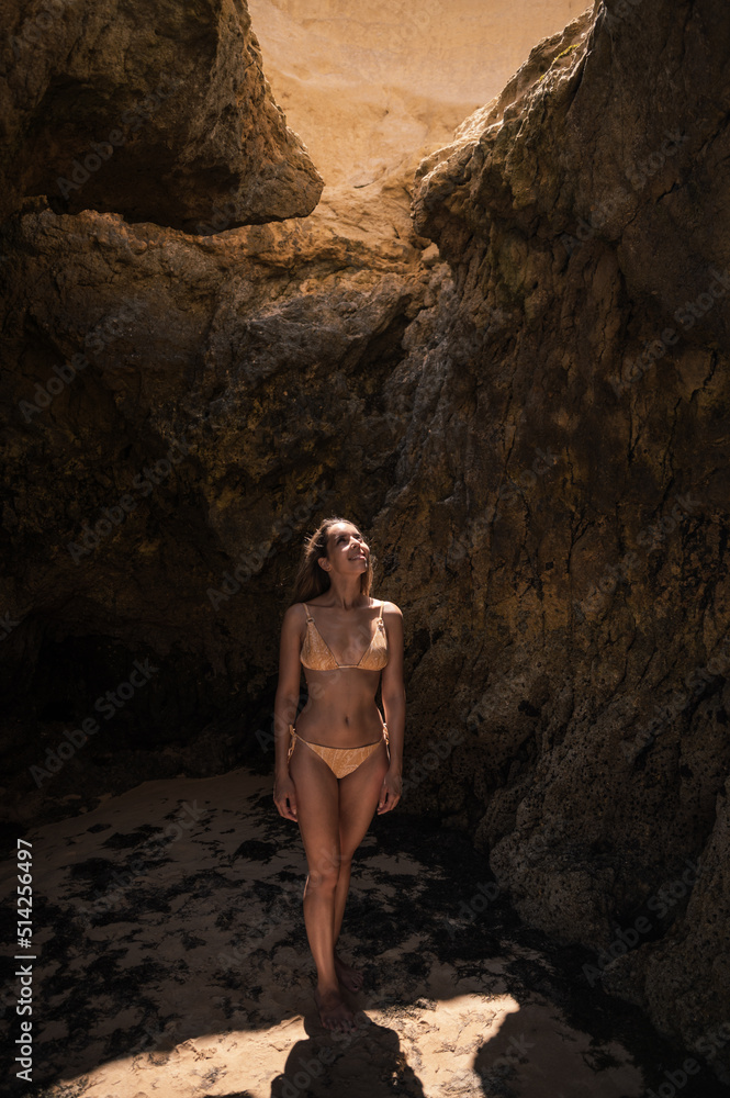 Woman in bikini standing near rock at seaside Woman in bikini standing near rock at seaside