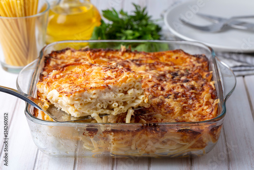 Pasta casserole bechamel sauce topped with melted mozzarella cheese and served in a white baking dish on a table (Turkish name; firinda makarna or firin makarna) photo