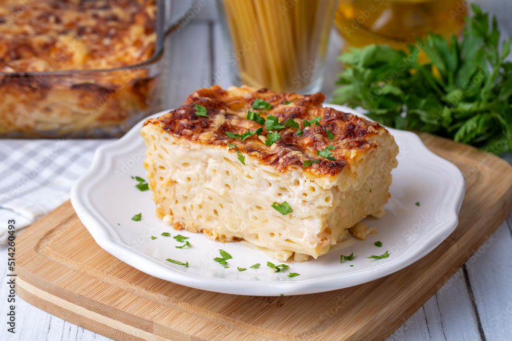 Pasta casserole bechamel sauce topped with melted mozzarella cheese and served in a white baking dish on a table (Turkish name; firinda makarna or firin makarna)