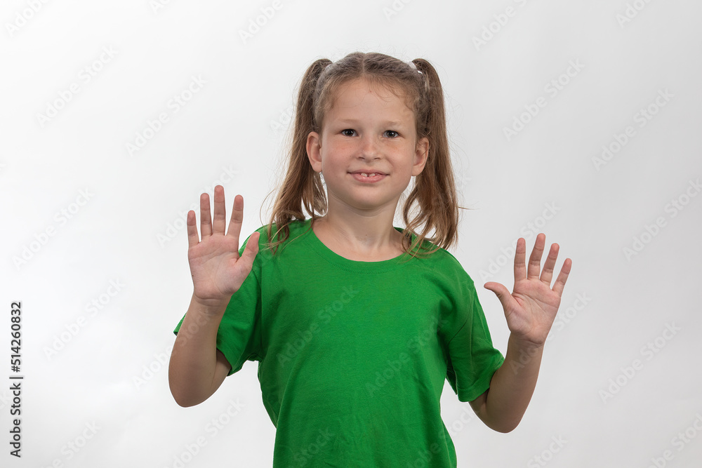 Smiling little girl holding up her hands in green t-shirt over white background Smiling little girl holding up her hands in green t-shirt over white background