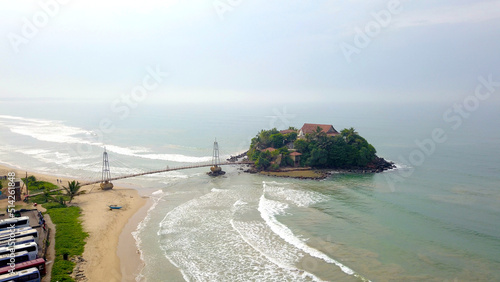 Small island off the coast of Sri Lanka seen from above. Located in the souther part of Sri Lanka, with a temple on the island, connected by a suspended bridge from the mainland photo
