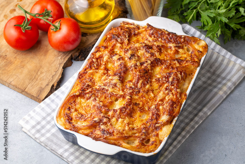 Pasta casserole bechamel sauce topped with melted mozzarella cheese and served in a white baking dish on a table (Turkish name; firinda makarna or firin makarna) photo