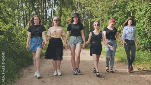 Fototapeta Naklejka Na Ścianę i Meble -  A group of girls are walking hand in hand outside the city.
