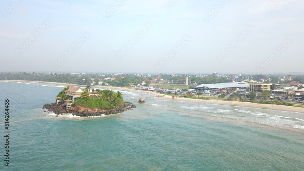 Small island off the coast of Sri Lanka seen from above. Located in the souther part of Sri Lanka, with a temple on the island, connected by a suspended bridge from the mainland