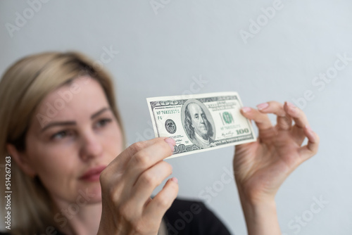 Canvas Print Woman holding dollar bill and looking at it with watermarks closeup